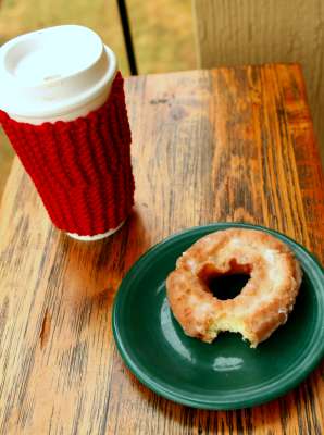 coffee mug with cozy and a donut
